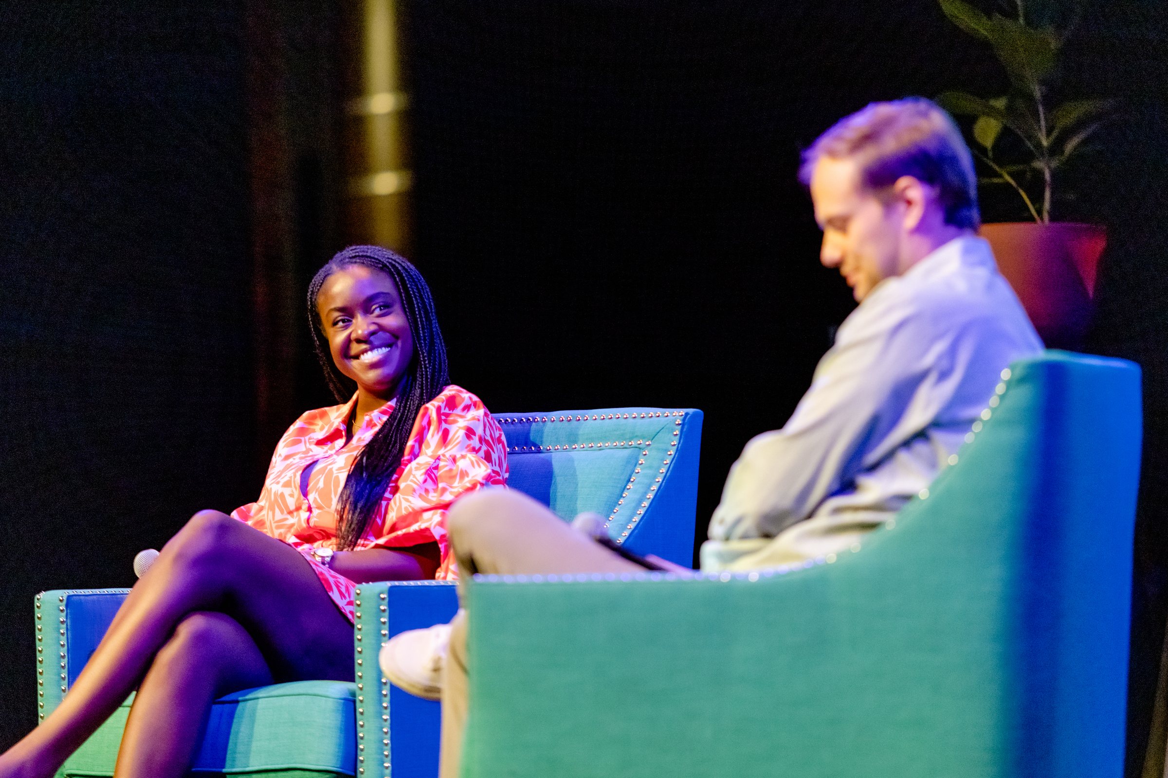 Two speakers in armchairs in conversation on a stage